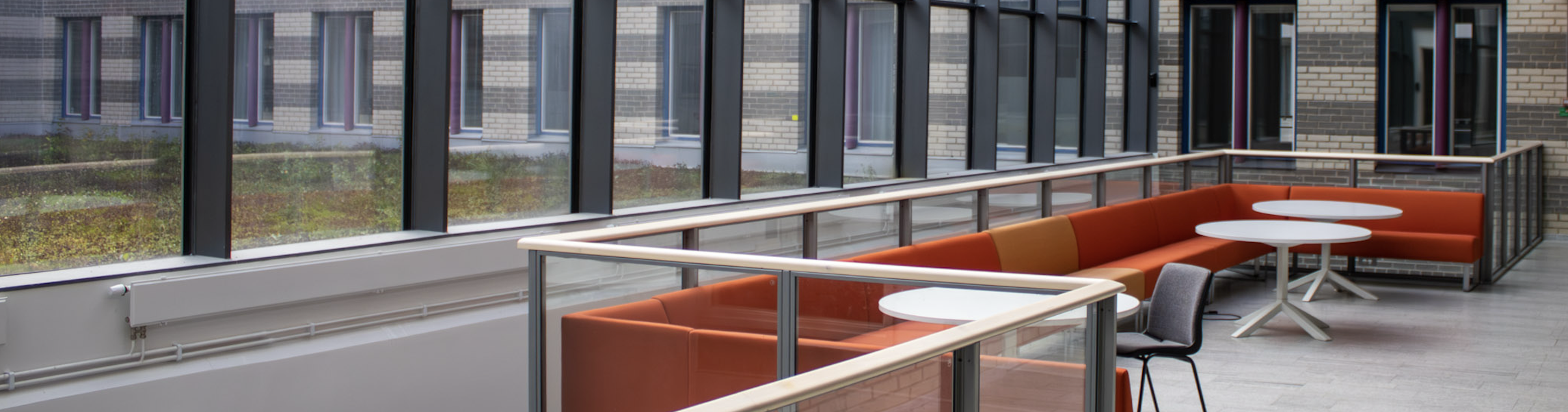 Röda soffor på ett överhäng framför stora fönster.